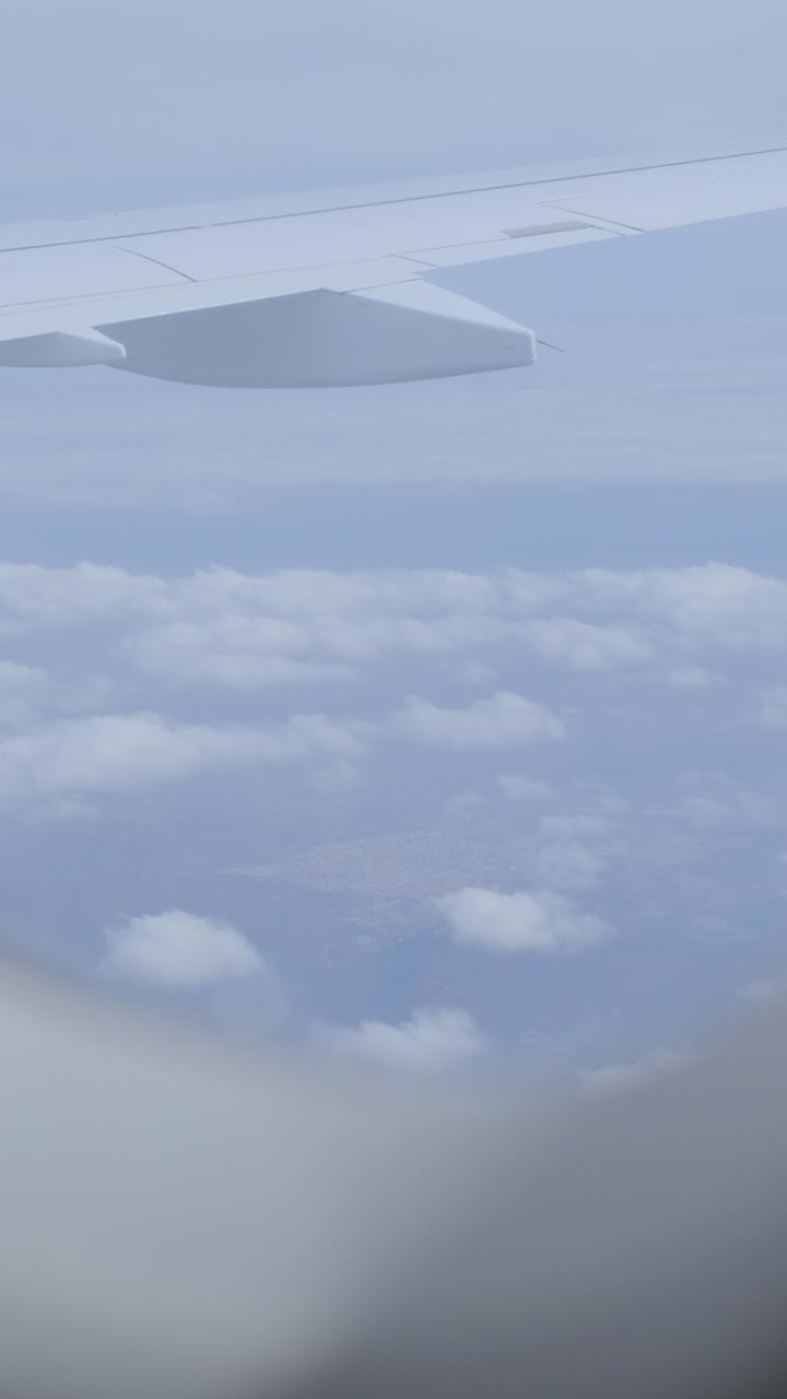 View from airplane window showing clouds and wing on a serene day