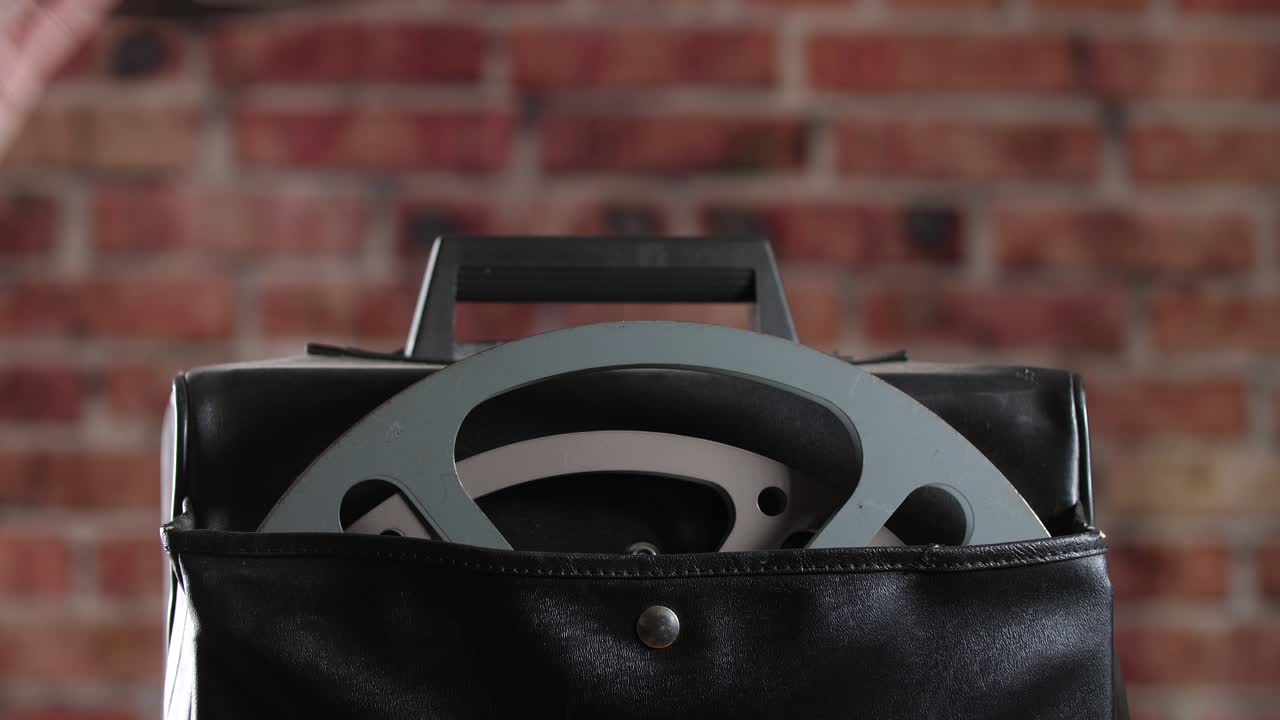 휴대용 16mm 필름 영사기를 프레임에 넣은 다음 케이스에서 필름 릴을 선택하는 클로즈업