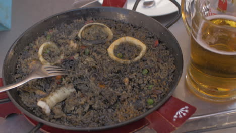 woman eating black paella with seafood