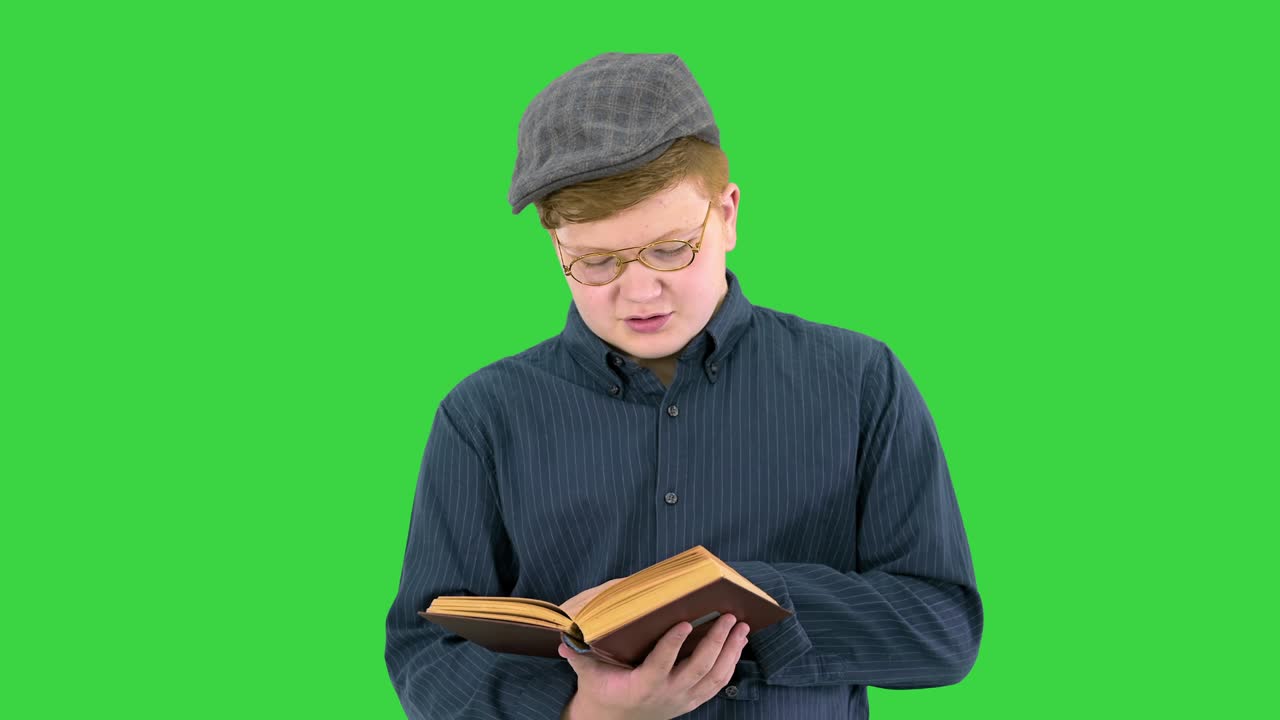 un joven elegante de pie y leyendo un libro en una pantalla verde, clave de croma