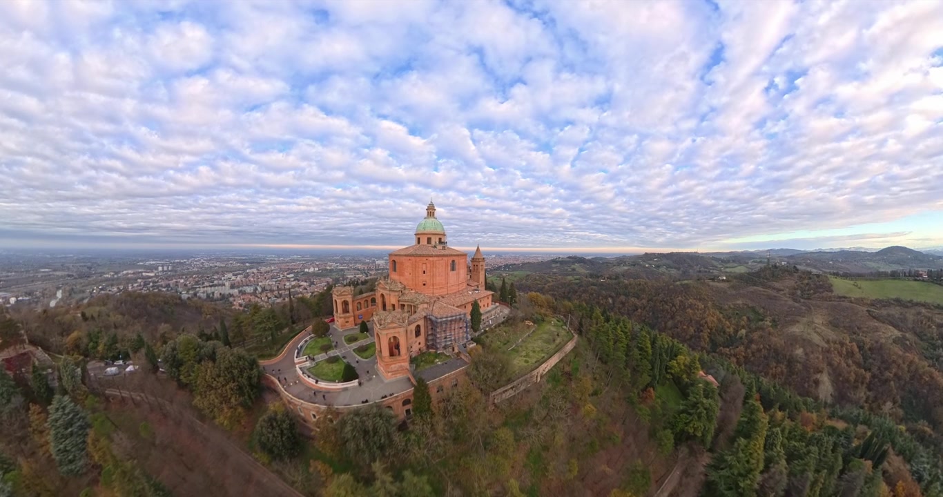 Forvrænget vidvinkel droneudsigt af den historiske helligdom Madonna di San Luca basilika på en skovklædt bakke med udsigt over Bologna, Italien. Luftfoto fremad, plads til tekst.