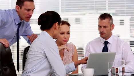 mujer de negocios mostrando a sus colegas algo en la computadora portátil