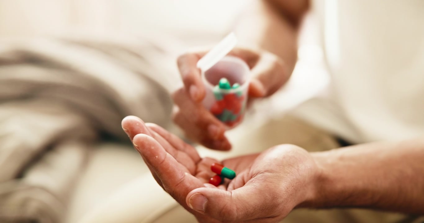 Man Pouring Medication Capsules Into His Hand