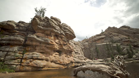 Tilt-down-slider-shot-of-unique-rock-formations-and-driftwood-at-Gem-Lake-in-Rocky-Mountain-National-Park