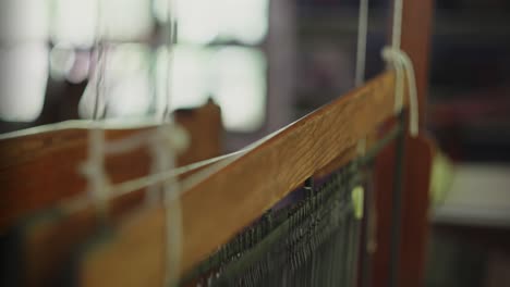 rearview of traditional hand weaving machine as worker pulls loom