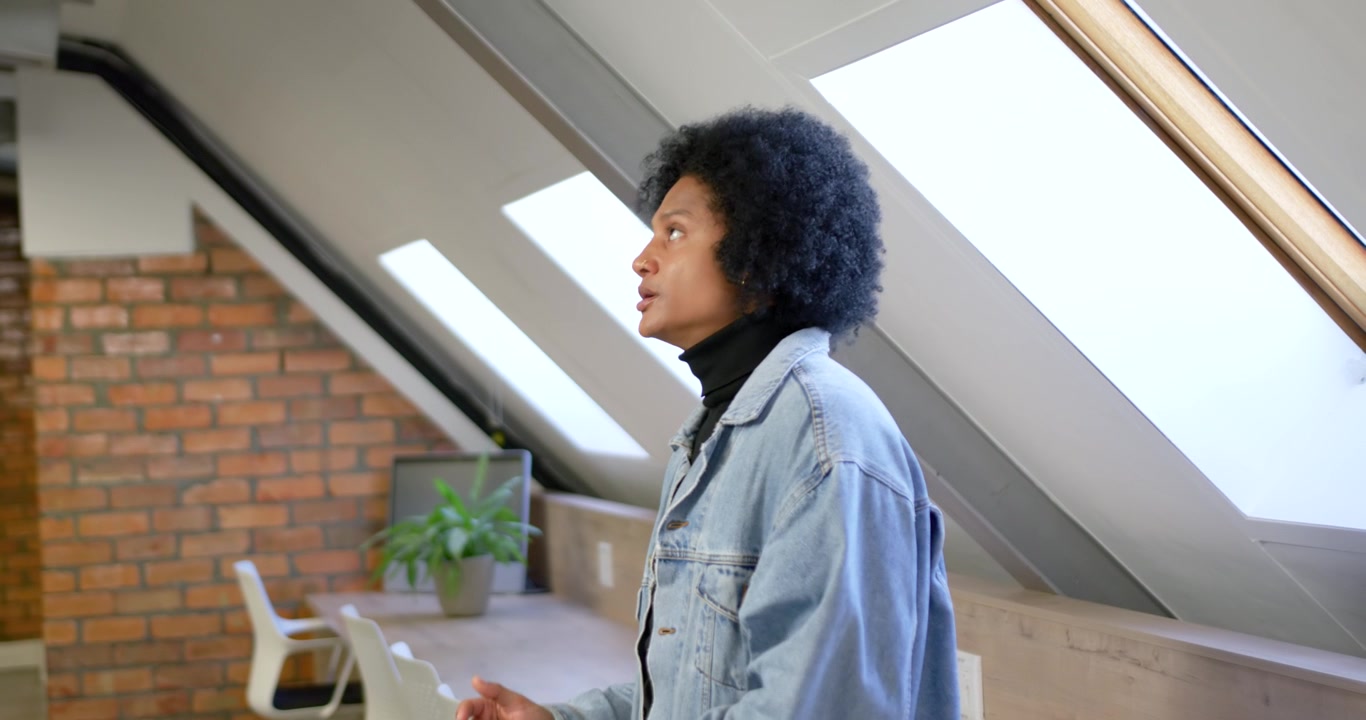 Adult male in denim jacket using phone scrolling then pausing noticing skylight glare, looking up