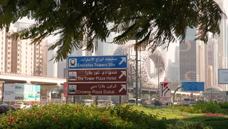 road traffic sign pointing to emirates towers, dubai, spring day, windy