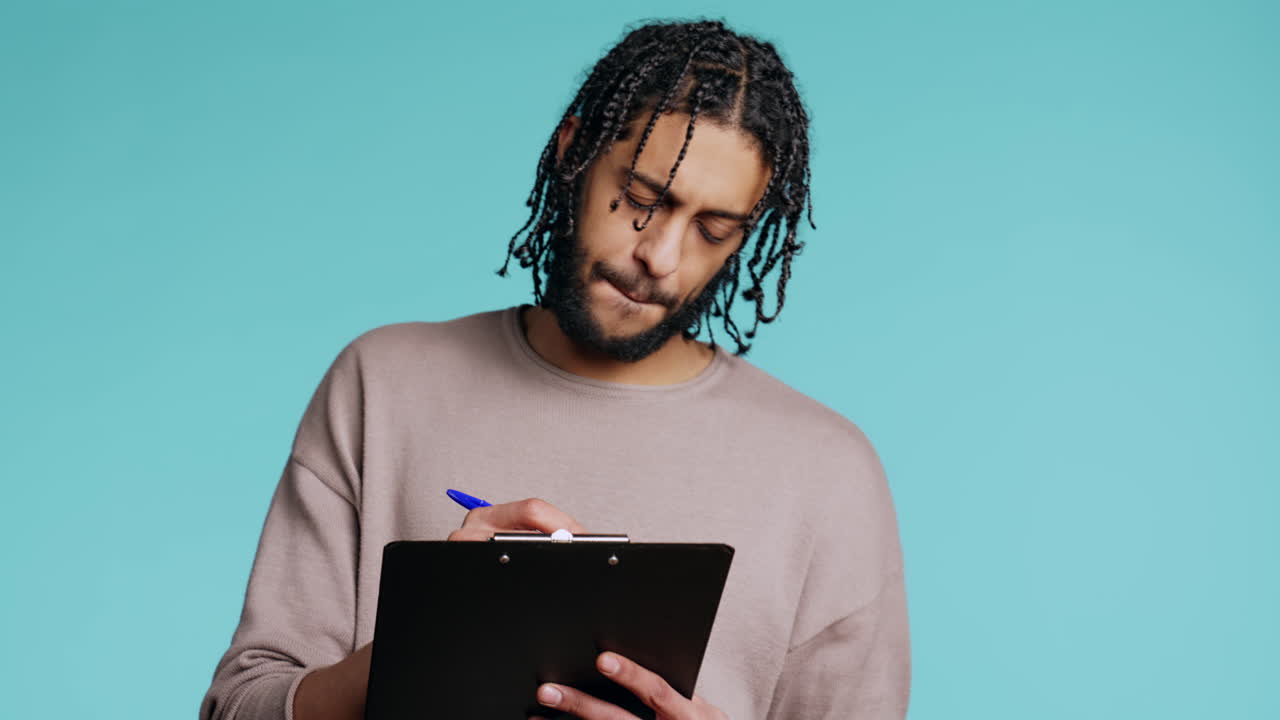 Creative man brainstorming ideas, writing on paper using pen, studio background