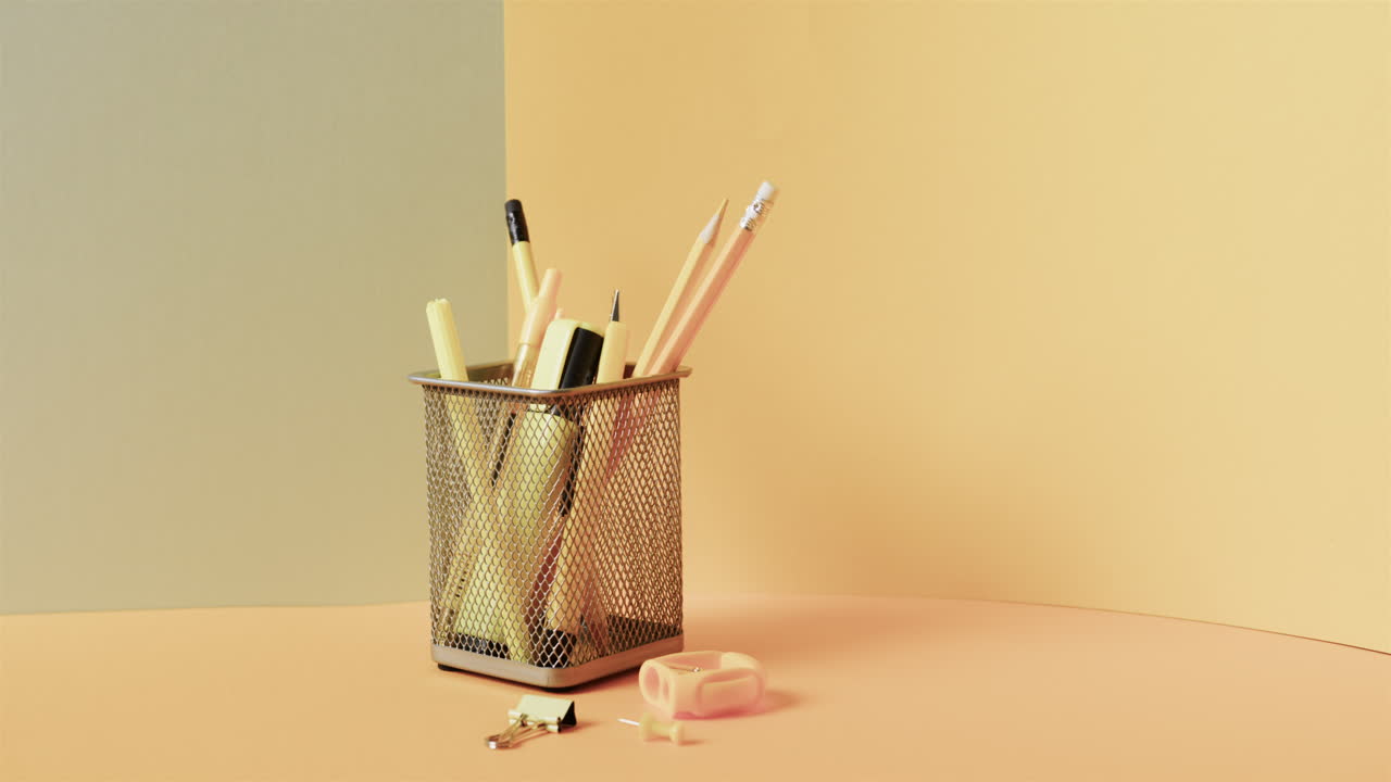 close up de papelería escolar en taza con espacio de copia en fondo amarillo, en cámara lenta