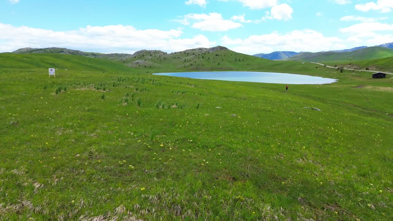 Vrazje jezero glacial lake beautiful green grasslands with a backdrop of rocky mountains in Durmitor National Park on Jezerska plateau, Aerial closeup