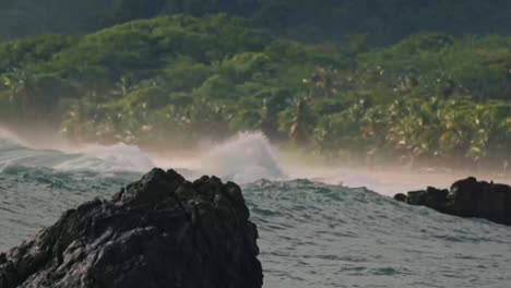a powerful wave crashes against the rocky shoreline of santa teresa, sending a dramatic spray of white water into the air