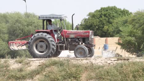 shot of man driving tractor in the farmland of pakistan