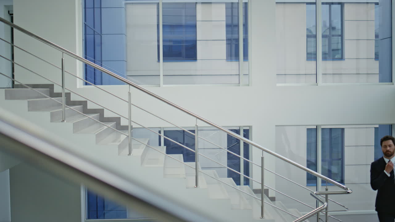 Company boss walking downstairs in elegant suit. Confident businessman going