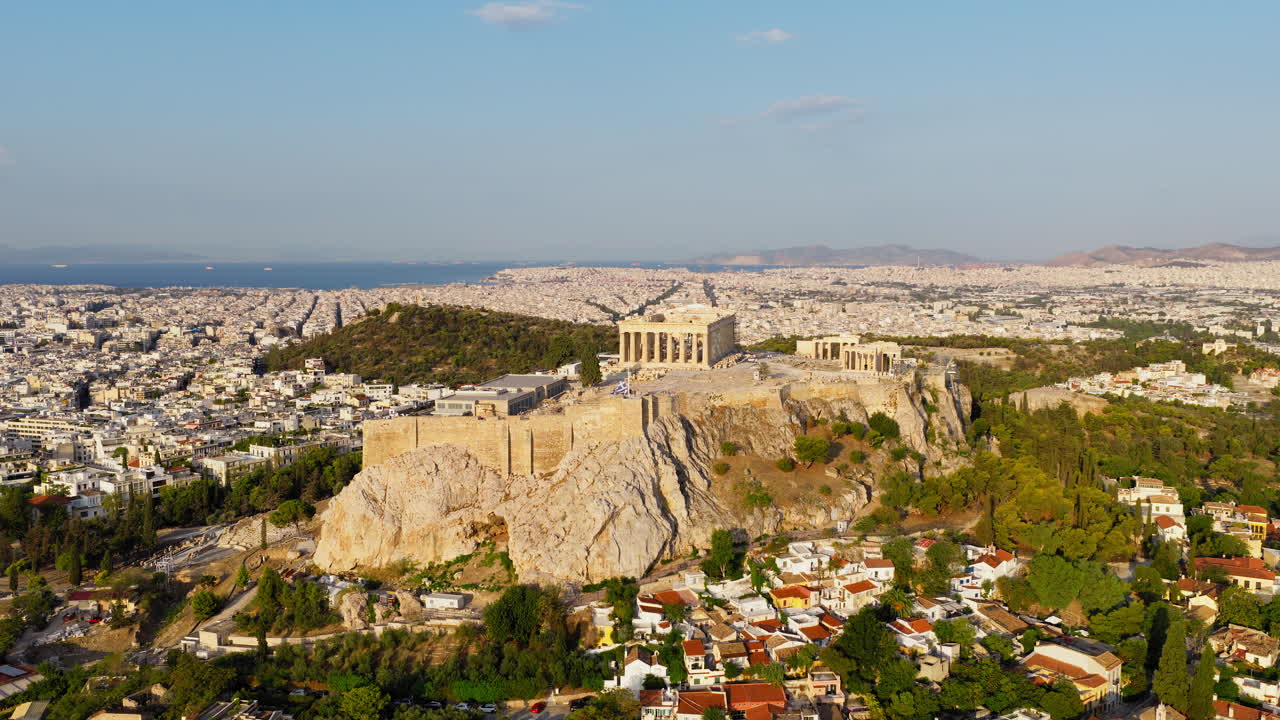Panci drone sinematik lambat di atas Parthenon dan Akropolis saat fajar, dengan cahaya lembut yang menampakkan tekstur reruntuhan kuno