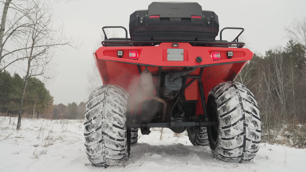 Primo piano posteriore di ATV, lancio estremo nella neve, potente accelerazione con vapore visibile dallo scarico, pneumatici con battistrada profondo che aderiscono al terreno ghiacciato, energia fuoristrada aggressiva e atmosfera ad alta adrenalina, macchina pronta.