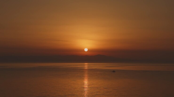 A beautiful sunset over the Aegean Sea, casting golden hues over the water and distant island.