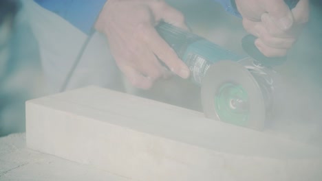 worker with a small angle grinder cuts a slab. stone processing from rock. marble cutting with grinding cutter