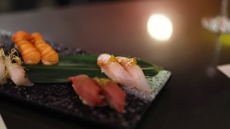 a hand selects sushi from an assorted platter.