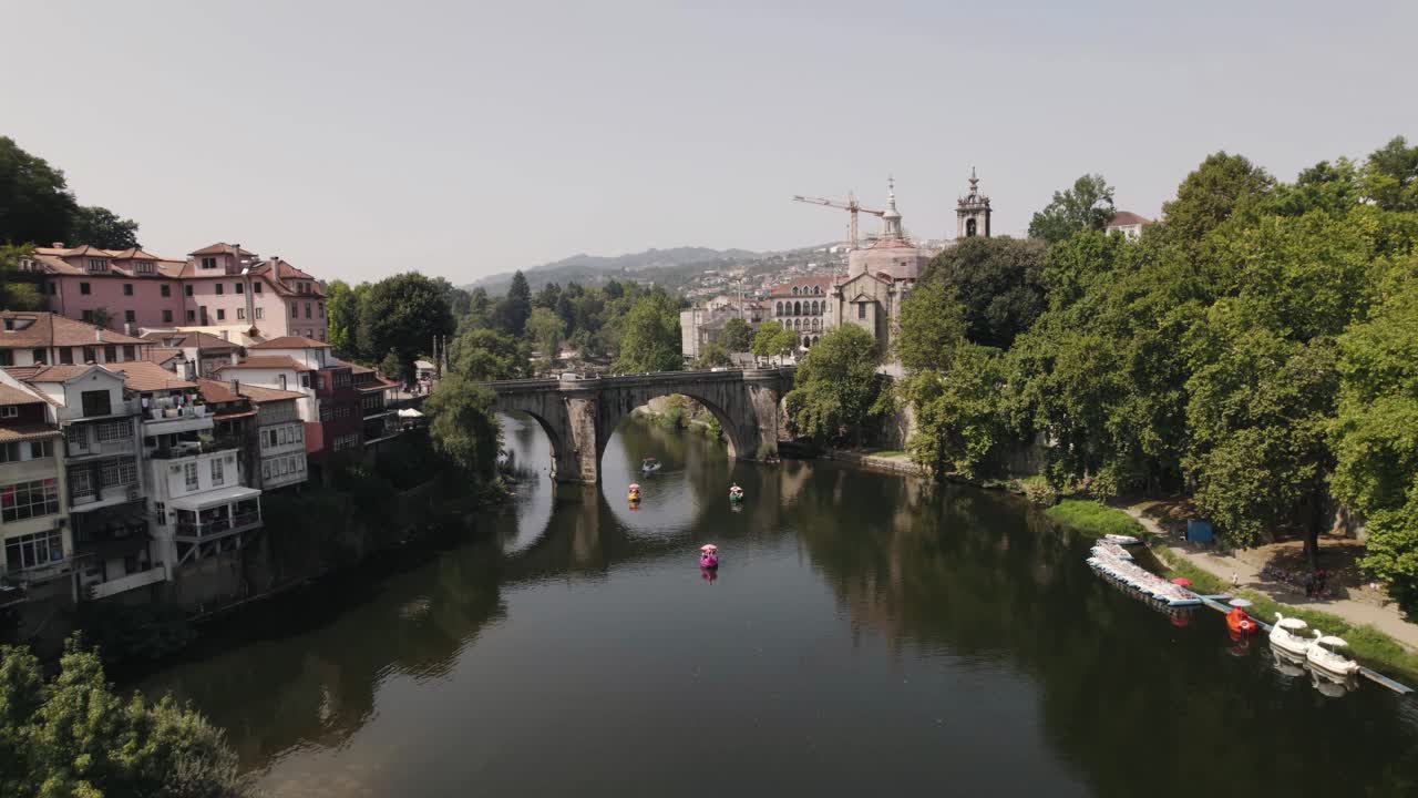 Luft-Schwenkaufnahme von Touristen, die tagsüber auf dem Tamega-Fluss unter der Brücke von São Gonçalo kreuzen.