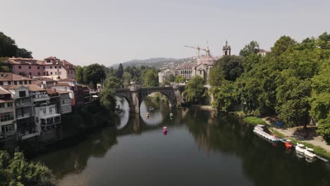 Aerial-pan-shot-overlooking-at-tourists-cruising-on-tamega-river-over-Sao-Goncalo-bridge-at-daytime