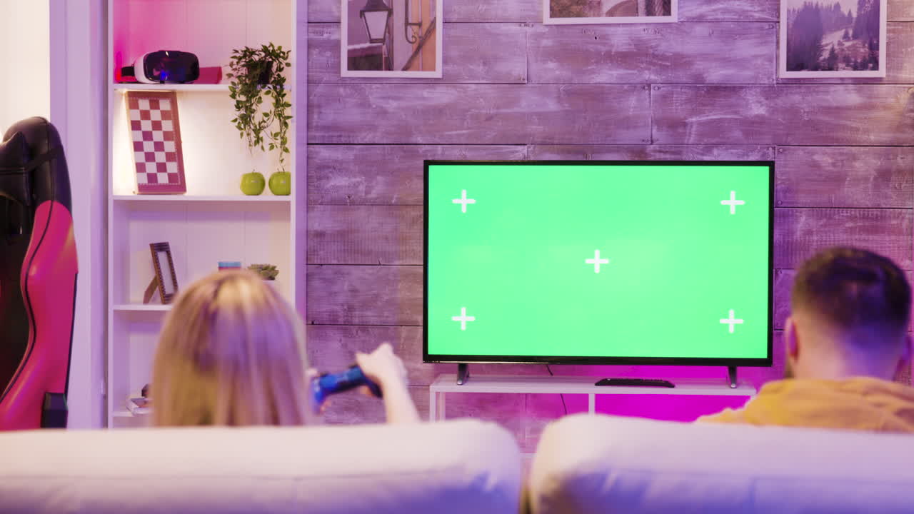 Couple playing video games on green screen TV