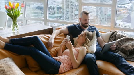 couple using digital tablet and mobile phone in living room 4k