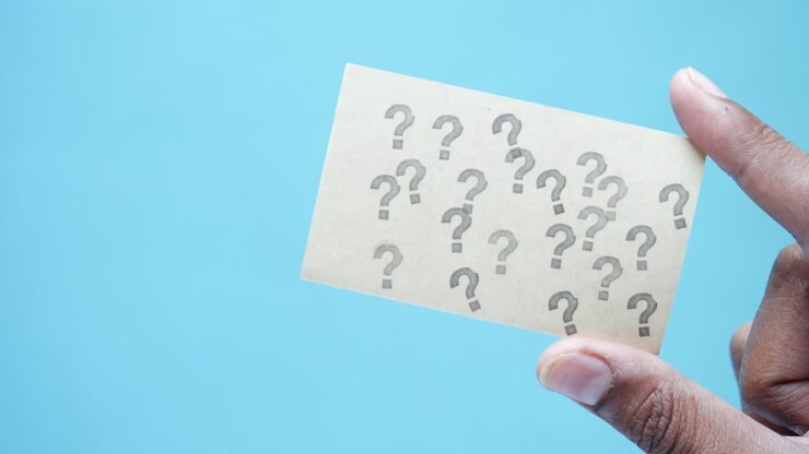 mano sosteniendo una tarjeta con múltiples signos de interrogación
