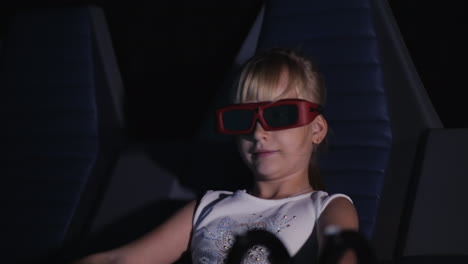 cool blonde girl is watching a movie in a 3d movie theater it blows the wind the seat rocks 4k video