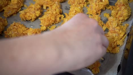 pollo crudo cubierto de copos de maíz en una bandeja para hornear