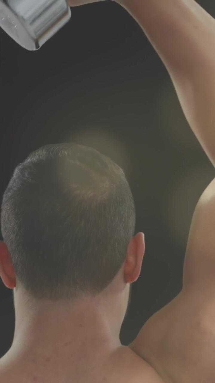 Vertical video: On cue, man performing overhead weight raises and lowers for shoulder strength