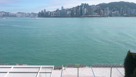 a pedestrian is seen strolling through victoria harbour waterfront as they enjoy their evening, sunset, and skyline view of hong kong island skyscrapers