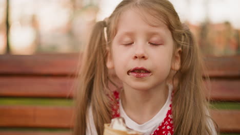 girl with ponytails eats ice cream with pleasure on bench