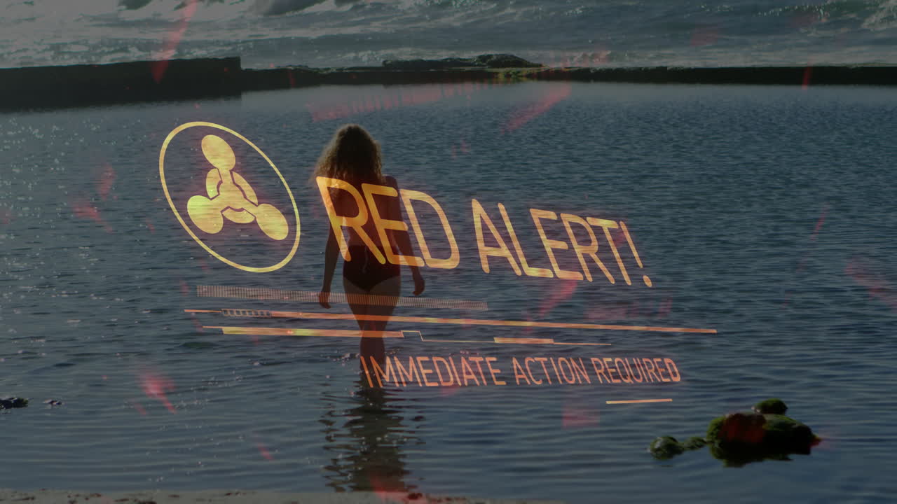 Red alert text animation over person walking into ocean water