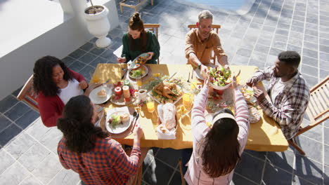 happy diverse male and female friends serving thanksgiving celebration meal in sunny garden