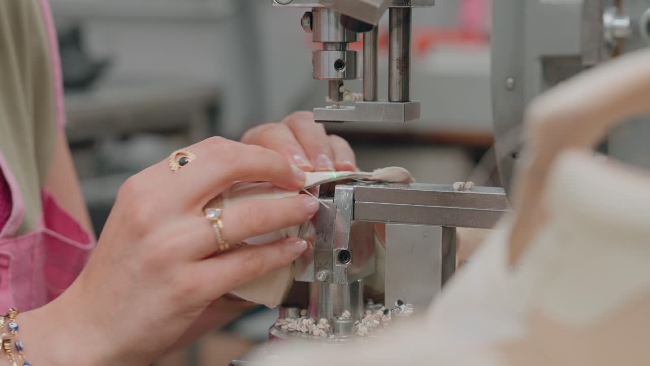 Hands operating industrial machine pressing material in factory