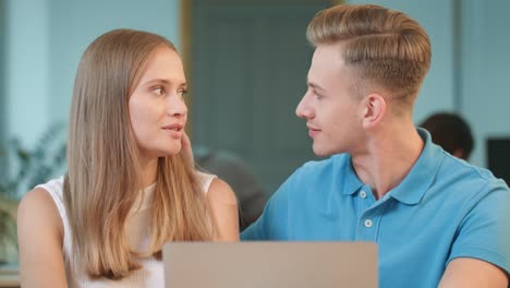 Young-man-flirting-with-girl-at-office.-Happy-colleagues-smiling-to-each-other