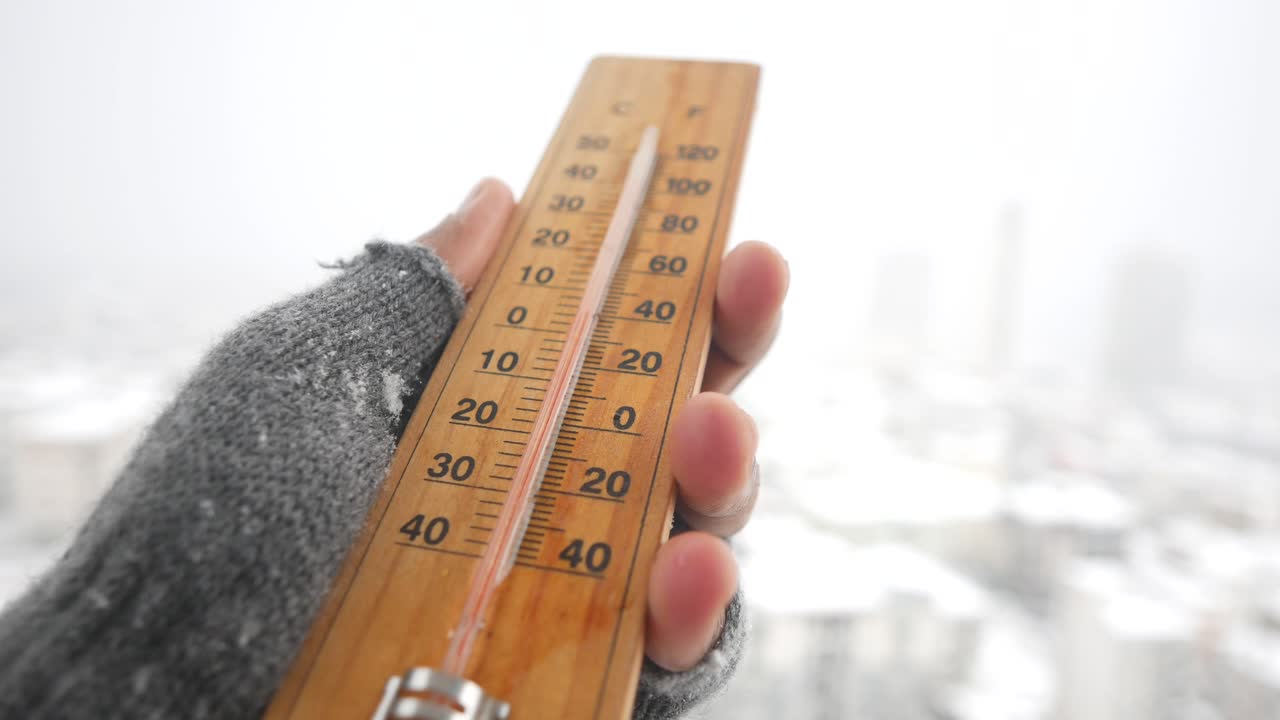 Hand with Glove Holding Thermometer in Snow