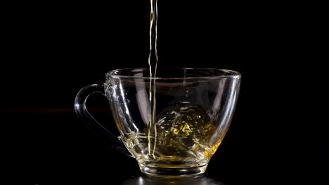 a sequence of tea being poured into a transparent glass cup against a dark backdrop, highlighting fluid motion and golden hues