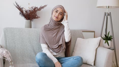 smiling woman in hijab sitting on a sofa