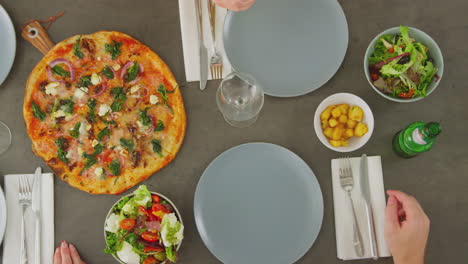 overhead view of friends eating pizza and drinking beer and wine in restaurant together