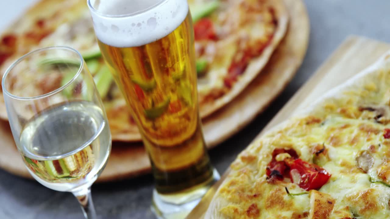 una deliciosa pizza con vasos de cerveza y vino