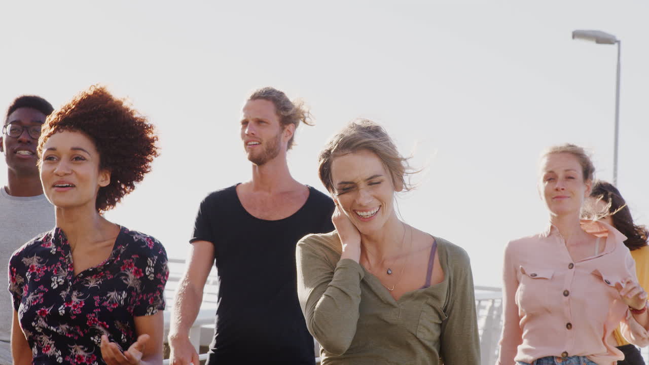 뜨거운 빛 에 대항 하여 다리 를 가로질러 함께 고 있는 젊은 친구 들 의 그룹