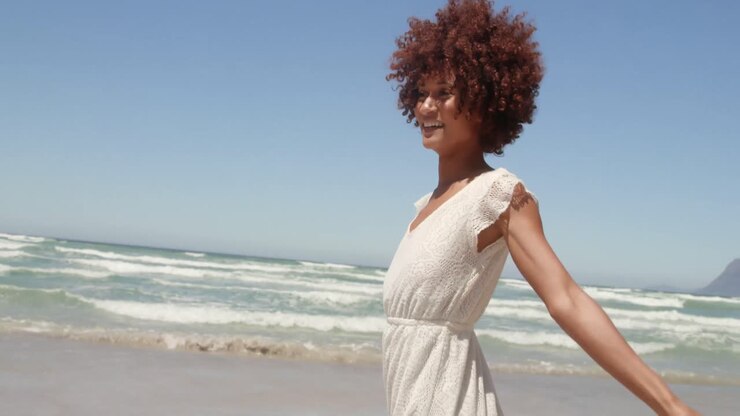 Front view of young African american woman having fun on beach in the sunshine 4k