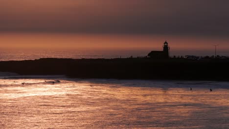 Drone-shot-at-late-sunset-golden-hour-over-the-ocean-with-a-lighthouse