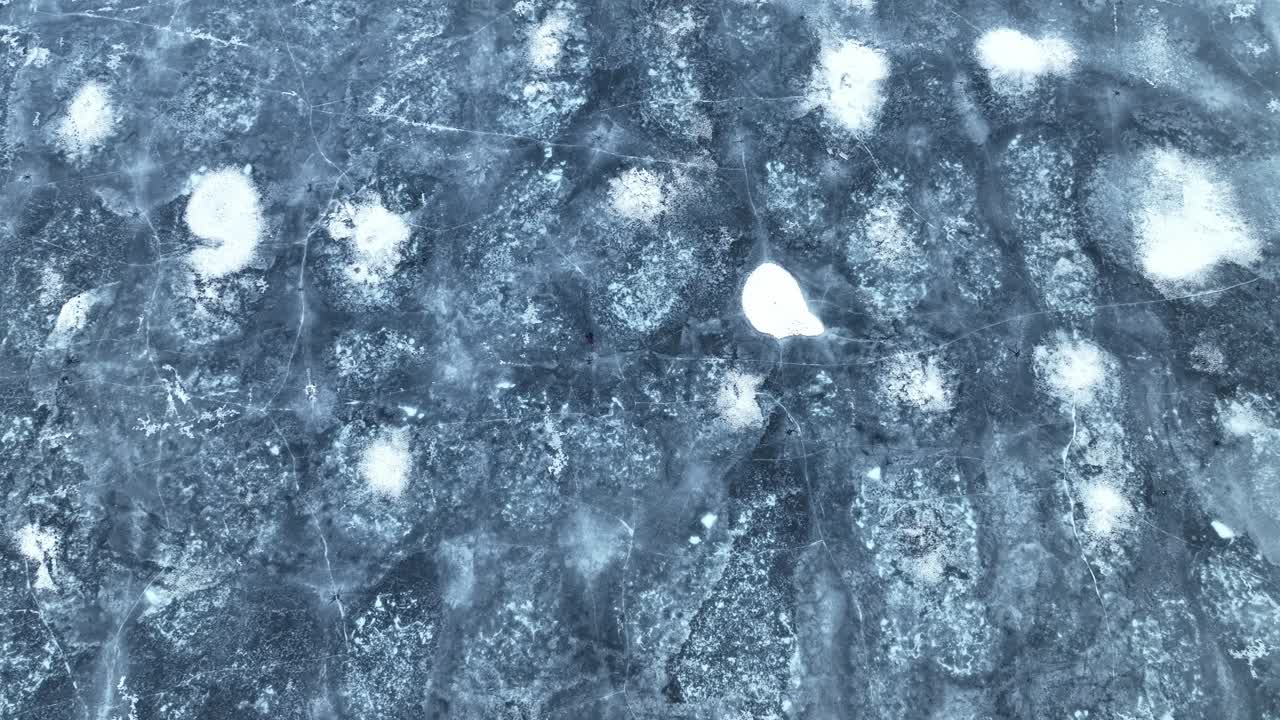 Una veduta aerea segue una donna che cammina sul ghiaccio di un fiordo ghiacciato mentre la telecamera si alza rivelando un vasto e isolato paesaggio invernale in Norvegia.