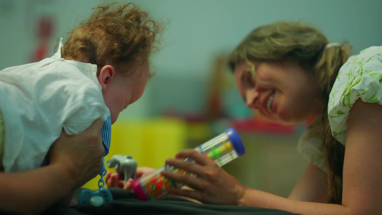 Baby experiencing sensory play with an adult, focusing on early childhood development and learning through interaction