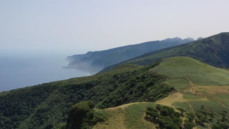 aerial view of green mountain hills above atlantic ocean, madeira island countryside, portugal on sunny day, drone shot