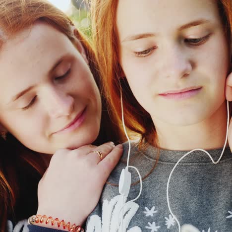 two red-haired twin sisters listen to music on headphones