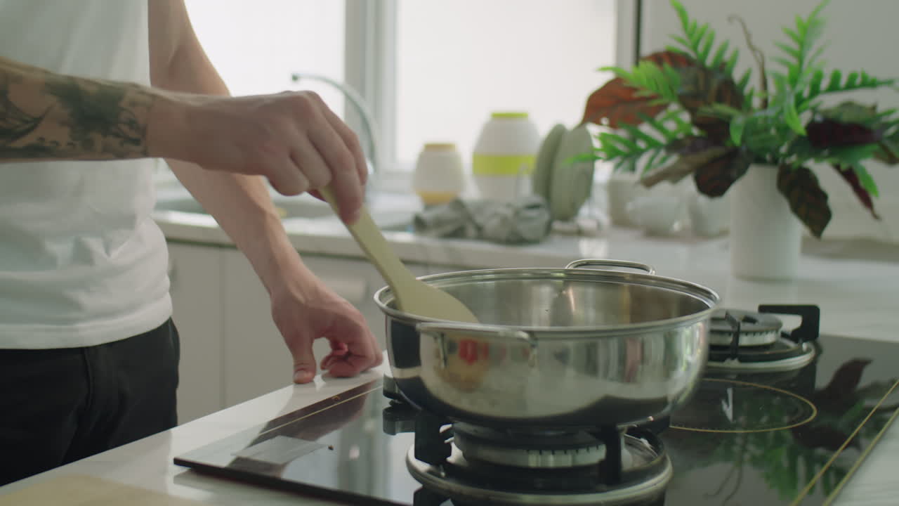 Man in Headphones Cooking Food on Kitchen Stove
