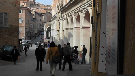 a woman with red jacket holding a bag walking out of an old architect building